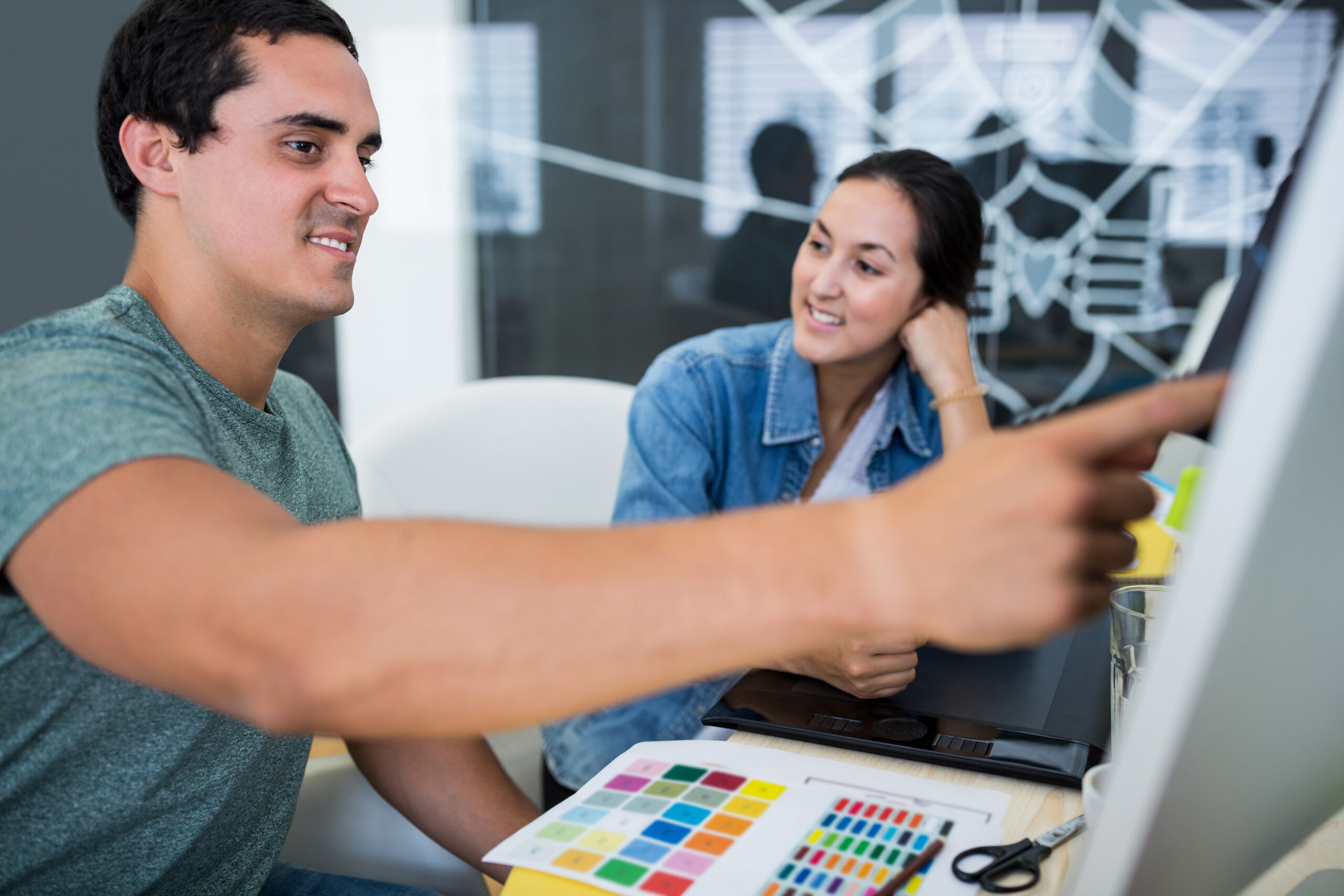 Male and female graphic designers interacting over computer